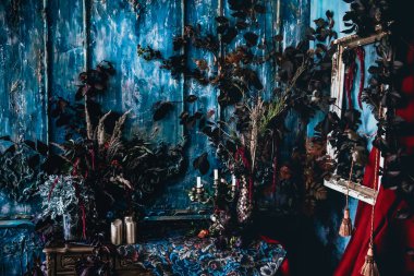 Kurumuş çiçekler, vazolar, avizeler, altın çerçeveli kumaşlar, lüks kraliyet tarzı ahşap bir masa, eski fenerlerle yanan mumlar.