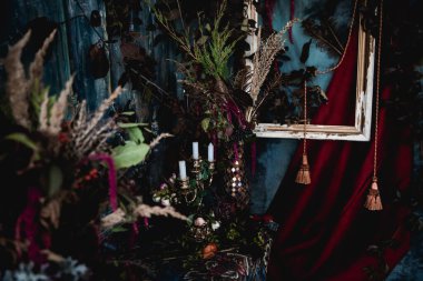 Kurumuş çiçekler, vazolar, avizeler, altın çerçeveli kumaşlar, lüks kraliyet tarzı ahşap bir masa, eski fenerlerle yanan mumlar.