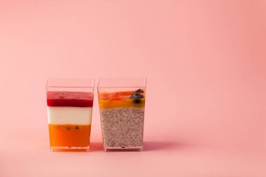 İki sulu tatlı, puding, chia tohumu, mango püresi, böğürtlen, çok katmanlı, panakota, pembe arka planda tutkulu hindistan cevizi sütü. metin için boşluk kopyala