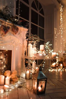 Noel iç tasarımında sıcak ve sıcak bir akşam, ışıklarla süslenmiş Xmas ağacı hediyeler, oyuncaklar, geyikler, mumlar, fenerler, kapalı alanda yanan şömine. tatil salonu sihirli yeni yıl