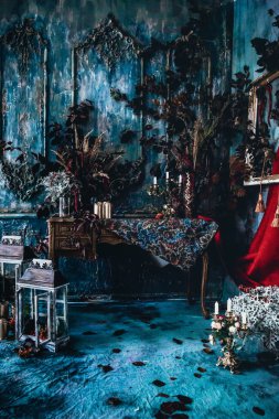 Kurumuş çiçekler, vazolar, avizeler, altın çerçeveli kumaşlar, lüks kraliyet tarzı ahşap bir masa, eski fenerlerle yanan mumlar.