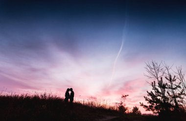 Çiftin silueti gün batımında sahada
