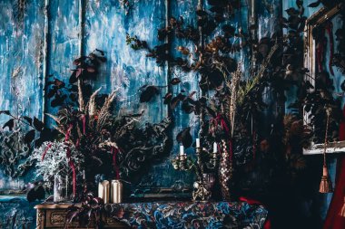 Kurumuş çiçekler, vazolar, avizeler, altın çerçeveli kumaşlar, lüks kraliyet tarzı ahşap bir masa, eski fenerlerle yanan mumlar.