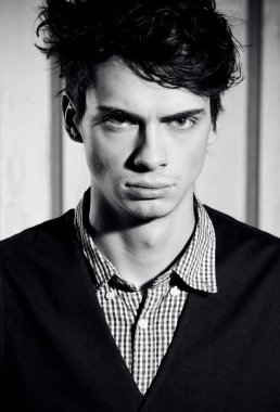 Stüdyoda poz veren gömlekli ve yelekli yakışıklı bir adam.