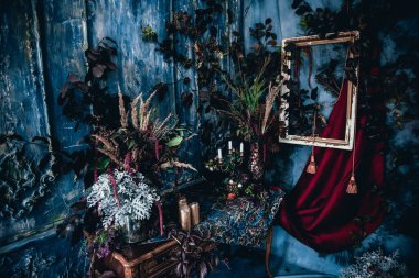 Kurumuş çiçekler, vazolar, avizeler, altın çerçeveli kumaşlar, lüks kraliyet tarzı ahşap bir masa, eski fenerlerle yanan mumlar.