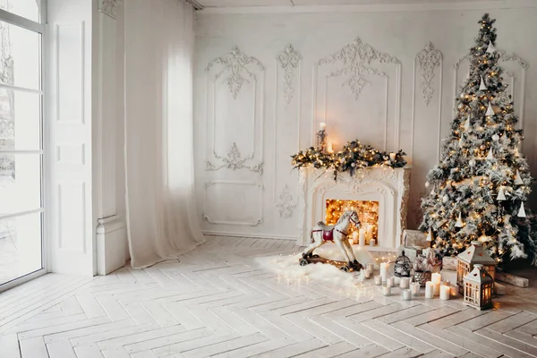 ガーランドとクリスマスツリーと白い部屋の古典的なインテリア 装飾された暖炉 ロッキングホース 新年のための贈り物 — ストック写真