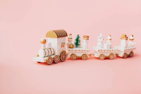holiday magic concept. New Year. postcard. small toy miniature white train with Santa, snowman, garland lights. Christmas tree, on pink crimson background in isolation. Copy space. Place text.