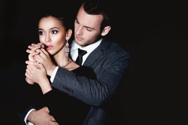 Çekici bir çift şık kıyafetler giyip geceleri dışarıda sarılıyorlar. 