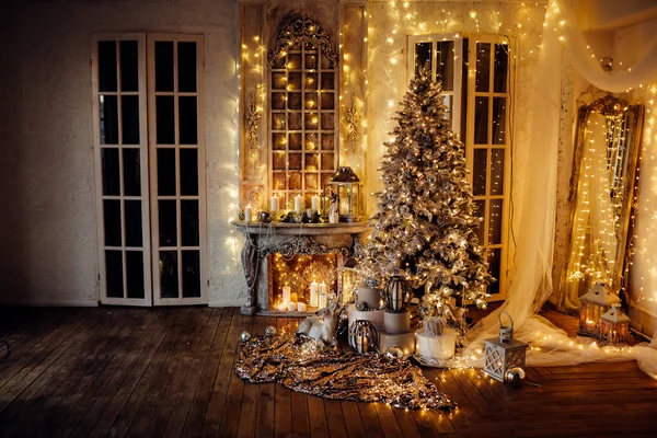 Noel iç tasarımında sıcak ve sıcak bir akşam, ışıklarla süslenmiş Xmas ağacı hediyeler, oyuncaklar, geyikler, mumlar, fenerler, kapalı alanda yanan çelenkler.