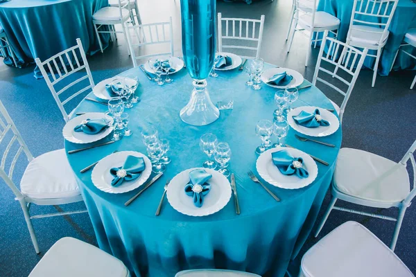Düğünde mavi ve beyaz renklerde güzel dekore edilmiş restoranlar masa örtüleriyle servis edilen masa örtüleri, tekstil peçeteleri vazolarda mavi suyla servis edilen çiçekler.