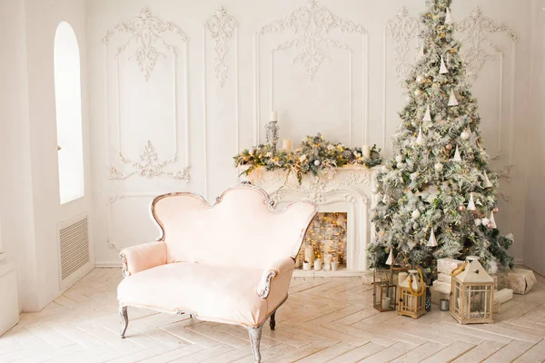 ピンクのソファが飾られた白い部屋の暖かくて居心地の良い古典的な高級インテリア暖炉 クリスマスツリー ガーランド キャンドル ランタン 朝の贈り物 新年明けましておめでとう — ストック写真