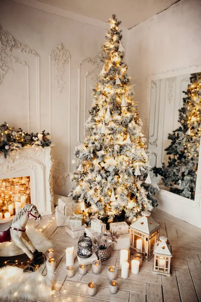 带有花环的圣诞树 装饰过的壁炉 摇曳的马 新年礼物的白色房间的经典内部 — 图库照片