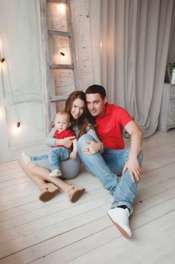 Mutlu ebeveynler, erkek bebekle odada poz veriyorlar.