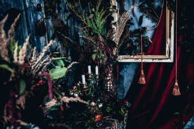 Kurumuş çiçekler, vazolar, avizeler, altın çerçeveli kumaşlar, lüks kraliyet tarzı ahşap bir masa, eski fenerlerle yanan mumlar.