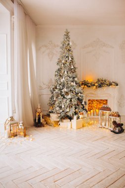 Süslü şöminesi, Noel ağacı, çelenkleri, mumları, fenerleri, sabahları hediyeleri olan beyaz bir odanın içi.