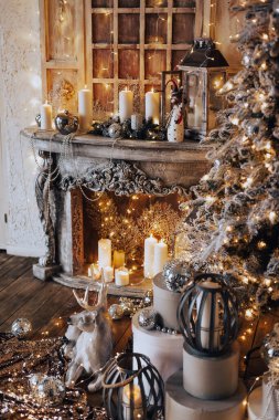 Noel iç tasarımında sıcak ve sıcak bir akşam, ışıklarla süslenmiş Xmas ağacı hediyeler, oyuncaklar, geyikler, mumlar, fenerler, kapalı alanda yanan çelenkler.