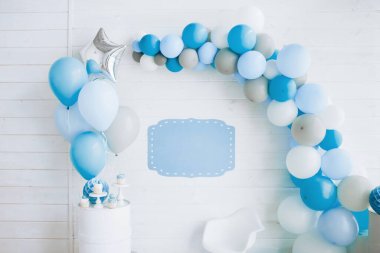 Balonlardan kemerle süslenmiş beyaz tahta bir duvar, mavi renk, boş yazı için bir tabak, mutlu yıllar konsepti.
