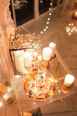 Noel iç tasarımında sıcak ve sıcak bir akşam, ışıklarla süslenmiş Xmas ağacı hediyeler, oyuncaklar, geyikler, mumlar, fenerler, kapalı alanda yanan şömine. tatil salonu sihirli yeni yıl