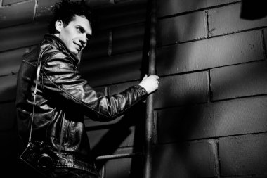 Duvarın yanında duran deri ceketli yakışıklı manken.