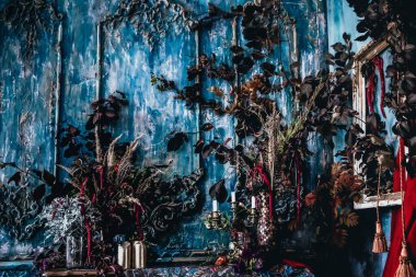 Kurumuş çiçekler, vazolar, avizeler, altın çerçeveli kumaşlar, lüks kraliyet tarzı ahşap bir masa, eski fenerlerle yanan mumlar.