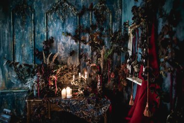 Kurumuş çiçekler, vazolar, avizeler, altın çerçeveli kumaşlar, lüks kraliyet tarzı ahşap bir masa, eski fenerlerle yanan mumlar.