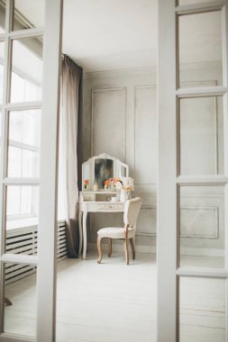 Güzel, beyaz bir iç mekan. Klasik oda ahşap zemin aydınlatma duvarları pervazlı tuvalet masası aynalı dekor ve çiçeklerle süslenmiş.