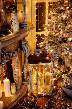 Noel iç tasarımında sıcak ve sıcak bir akşam, ışıklarla süslenmiş Xmas ağacı hediyeler, oyuncaklar, geyikler, mumlar, fenerler, kapalı alanda yanan çelenkler.