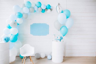 Balonlardan kemerle süslenmiş beyaz tahta bir duvar, mavi renk, boş yazı için bir tabak, mutlu yıllar konsepti.