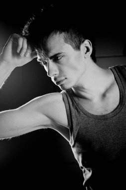 Yakışıklı model stüdyoda poz veriyor ve kafaya dokunuyor.