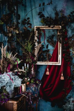 Kurumuş çiçekler, vazolar, avizeler, altın çerçeveli kumaşlar, lüks kraliyet tarzı ahşap bir masa, eski fenerlerle yanan mumlar.