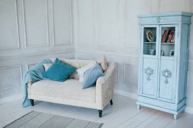 Kanepesi ve doğal renklerde yastıkları olan parlak oturma odası. Mavi ekose ve İskandinav tarzında gardırop.