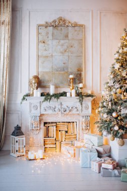 Noel ağacı ve dekoratif şömineyle süslenmiş, zarif, aydınlık renkte bir oda tasarımı.