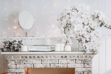 Beyaz oda içi Noel süsleri ve çiçeklerle dolu.