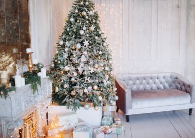 Noel ağacı ve dekoratif şömineyle süslenmiş, zarif, aydınlık renkte bir oda tasarımı.