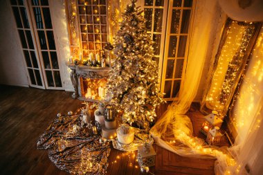 Noel odasında sıcak ve sıcak bir akşam, iç tasarım, ışıklarla süslenmiş Noel ağacı, oturma odası. Yeni yılda sihir.