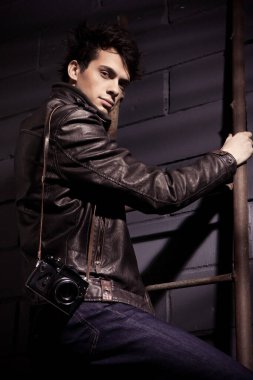 Duvarın yanında duran deri ceketli yakışıklı manken.