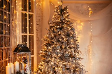 Noel iç tasarımında sıcak ve sıcak bir akşam, ışıklarla süslenmiş Xmas ağacı hediyeler, oyuncaklar, geyikler, mumlar, fenerler, kapalı alanda yanan çelenkler.