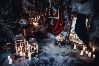 Kurumuş çiçekler, vazolar, avizeler, altın çerçeveli kumaşlar, lüks kraliyet tarzı ahşap bir masa, eski fenerlerle yanan mumlar.