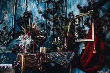 Kurumuş çiçekler, vazolar, avizeler, altın çerçeveli kumaşlar, lüks kraliyet tarzı ahşap bir masa, eski fenerlerle yanan mumlar.