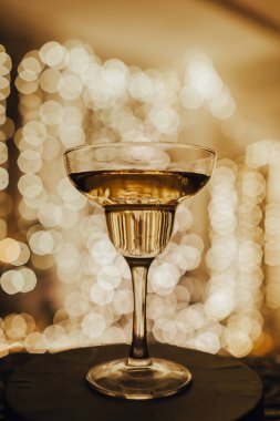 Bulanık bokeh noktalarının üzerine bir kadeh şampanya. Arka planda ışıklar. Lüks kutlama konsepti. Altın dekor