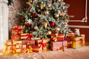 Noel ağacı, hediyeler, şömine ve çelenklerle süslü bir iç dizayn.