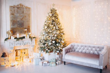 Noel ağacı ve dekoratif şömineyle süslenmiş, zarif, aydınlık renkte bir oda tasarımı.