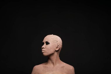 Siyah arka planda kilden maskeli kel bir kadın.