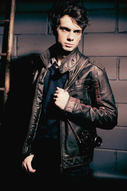 Duvarın yanında duran deri ceketli yakışıklı manken.