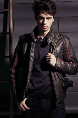 Duvarın yanında duran deri ceketli yakışıklı manken.