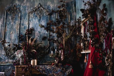 Kurumuş çiçekler, vazolar, avizeler, altın çerçeveli kumaşlar, lüks kraliyet tarzı ahşap bir masa, eski fenerlerle yanan mumlar.