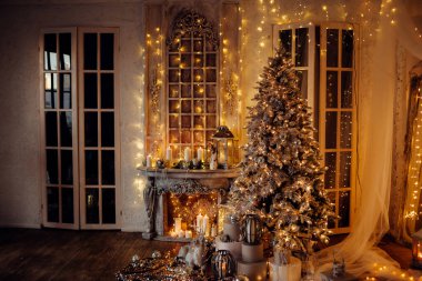 Noel iç tasarımında sıcak ve sıcak bir akşam, ışıklarla süslenmiş Xmas ağacı hediyeler, oyuncaklar, geyikler, mumlar, fenerler, kapalı alanda yanan çelenkler.