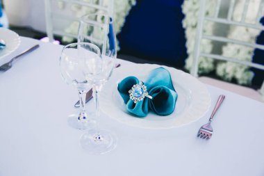 Beyaz çiçekli düğün masası ve kristalli mavi peçeteler.