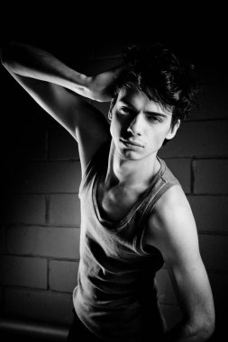 Yakışıklı model stüdyoda poz veriyor ve kafaya dokunuyor.