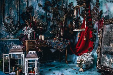 Kurumuş çiçekler, vazolar, avizeler, altın çerçeveli kumaşlar, lüks kraliyet tarzı ahşap bir masa, eski fenerlerle yanan mumlar.